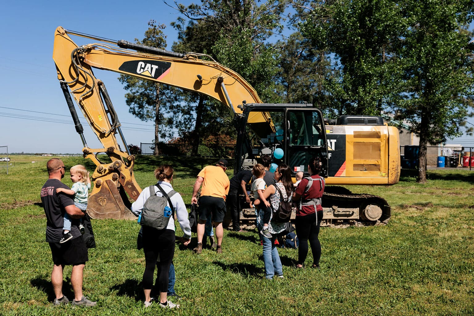 Kids with their parents near an excavator for composting at the WPWMA