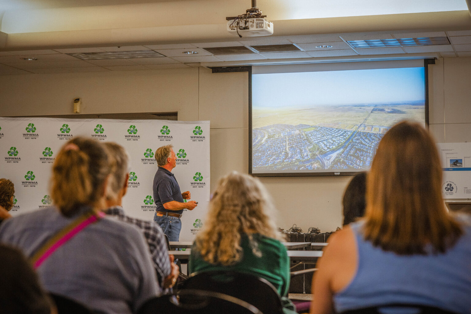 Man presents an aerial photo showing land surrounding the Western Placer Waste Management Authority at front of classroom full of event attendees