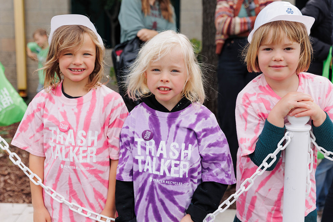 Three young girls smiling for the camera wearing matching "Trash Talker" tie-dye t-shirts with Placer Recycles branding at the WPWMA Trash Bash event