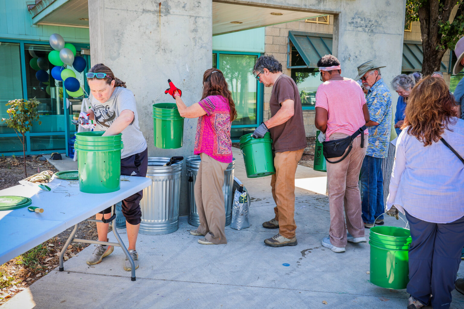 Attendees collect green waste material and place into green buckets with holes drilled into them to create compost