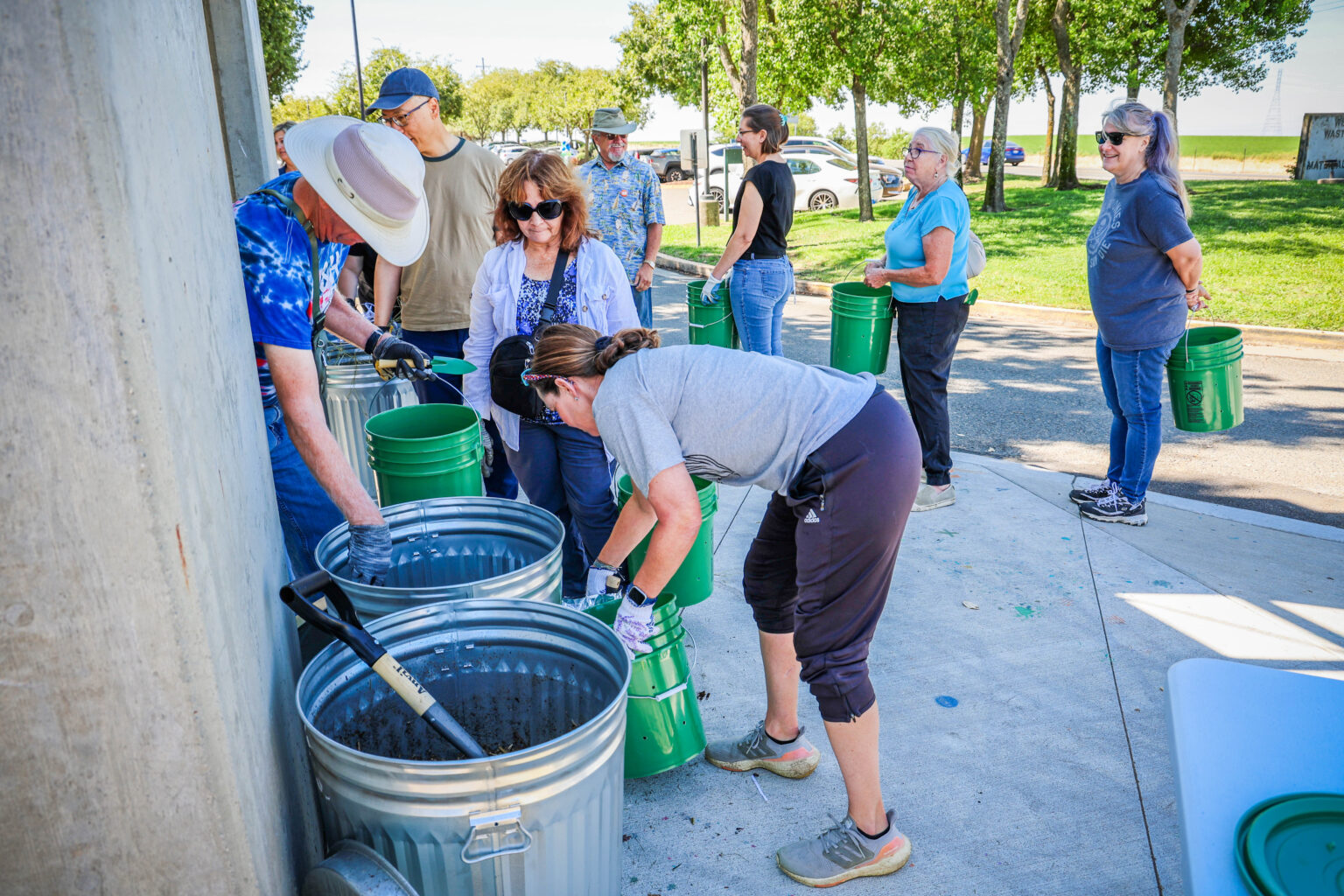 Attendees collect green waste material and place into green buckets with holes drilled into them to create compost
