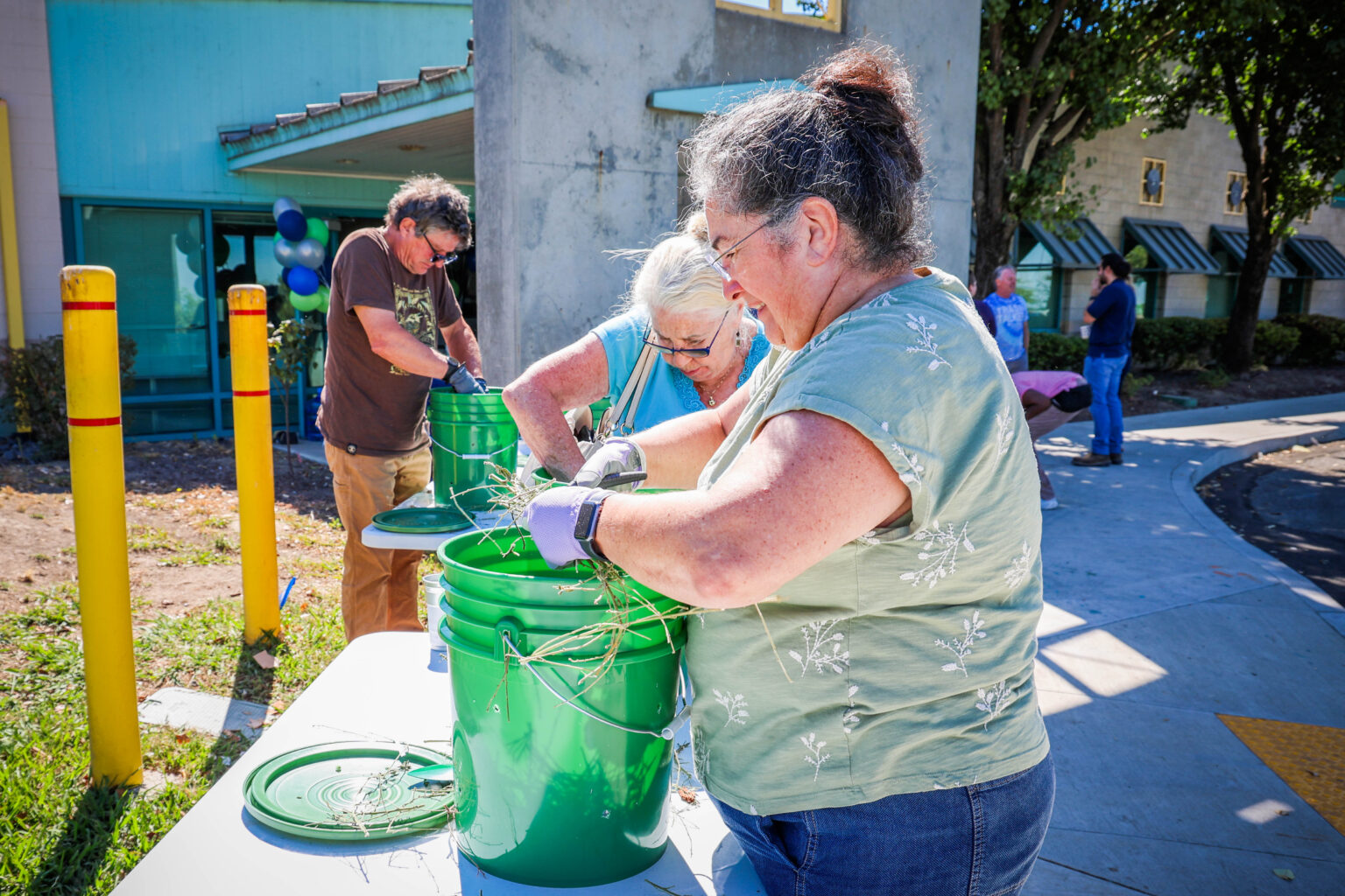 Attendees trim green waste material and place into green buckets with holes drilled into them to create compost