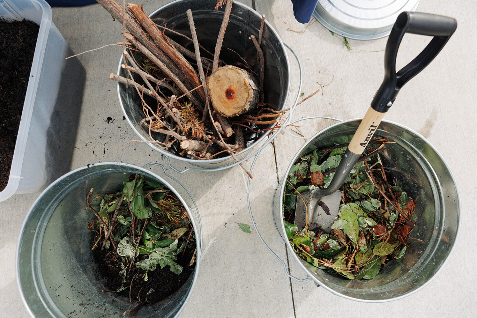 Top view of three galvanized steel buckets are being used to collect organic materials for composting.